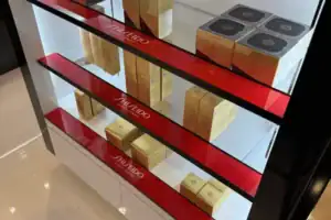 Detail Of Red And Gold Acrylic Risers Displaying Shiseido Cosmetics In A Lighted Case