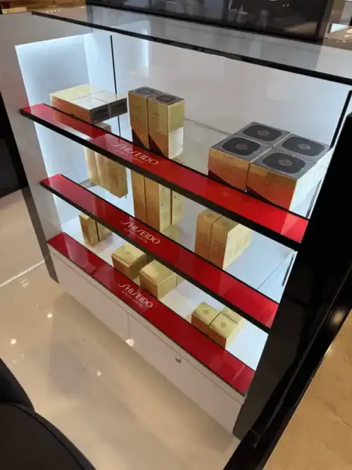 Detail of Red and Gold Acrylic Risers Displaying Shiseido Cosmetics in a Lighted Case
