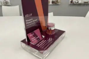 Clear Acrylic Counter Riser With Printed Backer Displaying Vella Skincare Products