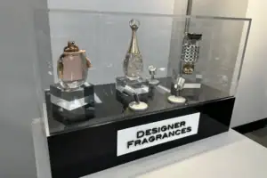 Black And Clear Acrylic Riser Displaying Designer Fragrance Bottles In A Glass Showcase