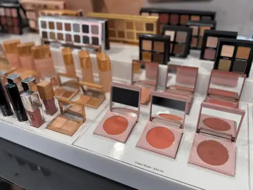 Clear Acrylic Risers Presenting Makeup Palettes and Cosmetics on a Retail Counter