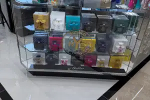 Clear Acrylic Display Case With Tiered Rows Of Perfume Bottles On A Store Counter