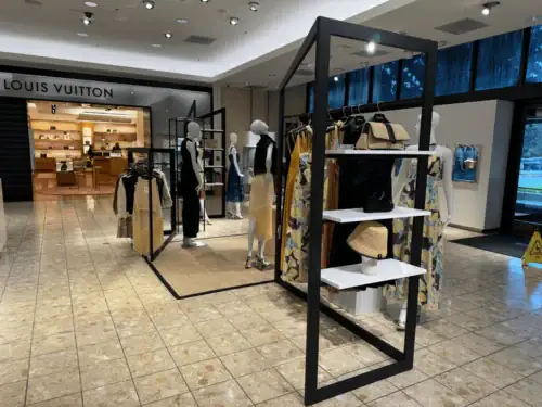 Black Metal Frame Clothing Display Rack With Hanging Apparel and Shelf