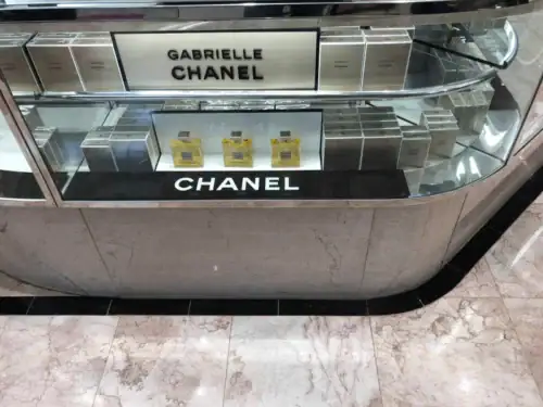 Curved Stone-Look Cosmetics Counter With Chanel Branding and Glass Display Top