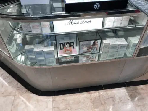 Curved Cosmetics Counter With Dior Branding, Glass Showcase and Stone-Look Base