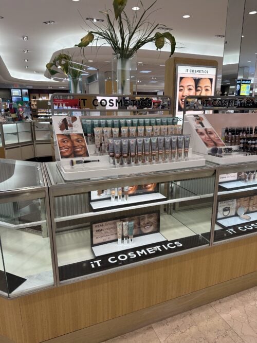 IT Cosmetics island counter with acrylic product displays and lighted graphics in a department store