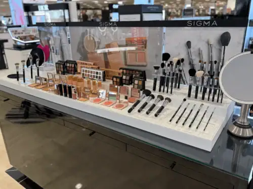 White Counter Display With Acrylic Holders Presenting Sigma Makeup Brushes and Cosmetics