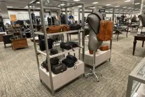 Metal Shelf Fixture With Fabric-Wrapped Base Displaying Handbags On A Retail Floor