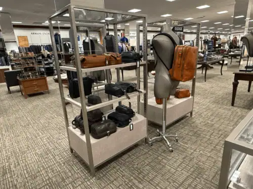 Metal Shelf Fixture With Fabric-Wrapped Base Displaying Handbags on a Retail Floor